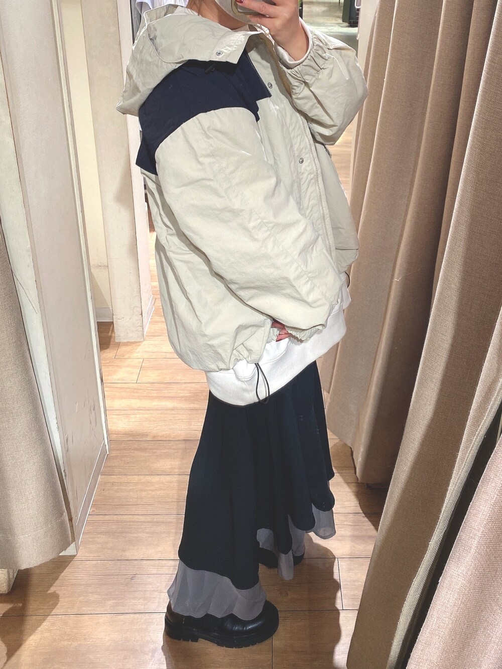 ベージュ系のマウンテンパーカー、ホワイト系のスウェット、ブラック系のスカートを着用したレディースの冬コーディネートの3枚目の写真