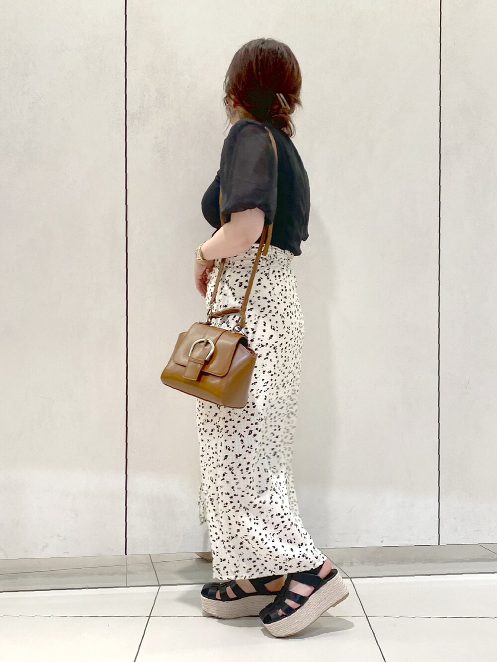 ブラック系のTシャツ/カットソー、ホワイト系のスカート、ブラック系のサンダルを着用したレディースの春コーディネートの2枚目の写真