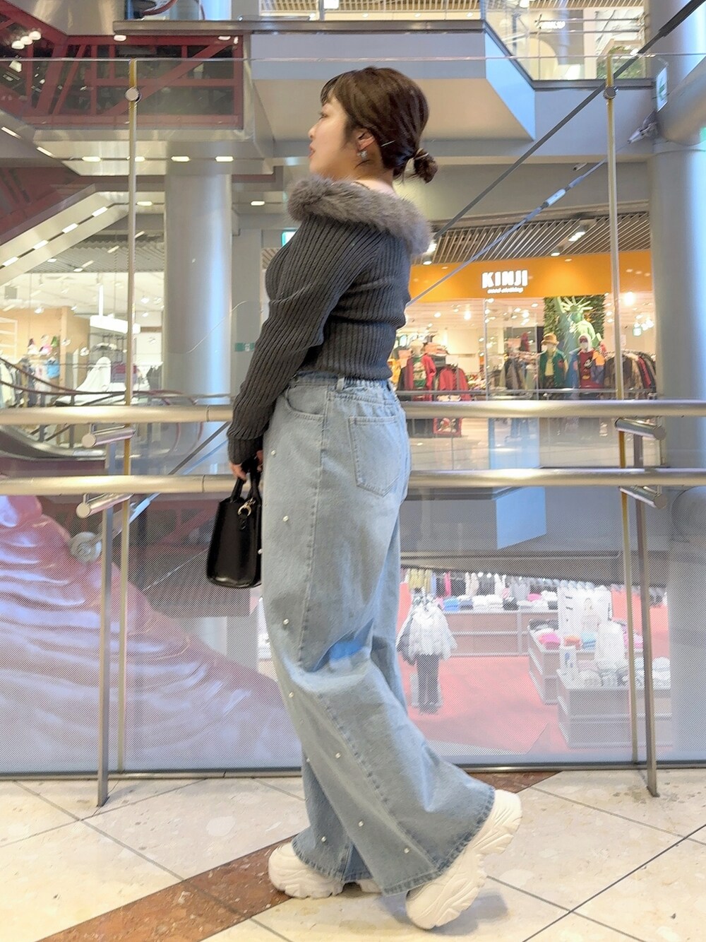 グレー系のニット/セーター、ブルー系のデニムパンツ、ブラック系のショルダーバッグを着用したレディースの冬コーディネートの2枚目の写真