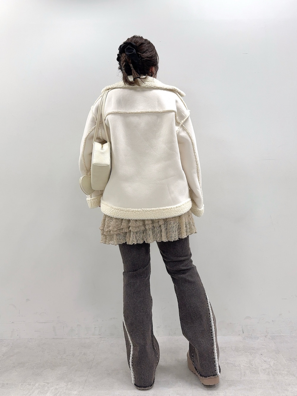 ホワイト系のブルゾン、ベージュ系のワンピース、ブラック系のデニムパンツを着用したレディースの秋コーディネートの3枚目の写真