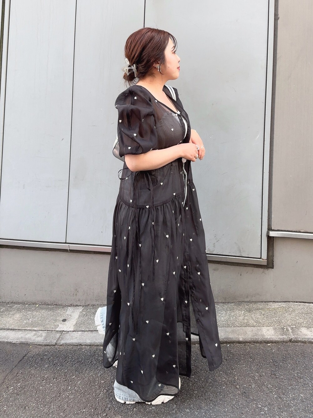 ブラック系のワンピース、ブルー系のデニムパンツ、ホワイト系のスニーカーを着用したレディースの春コーディネートの2枚目の写真