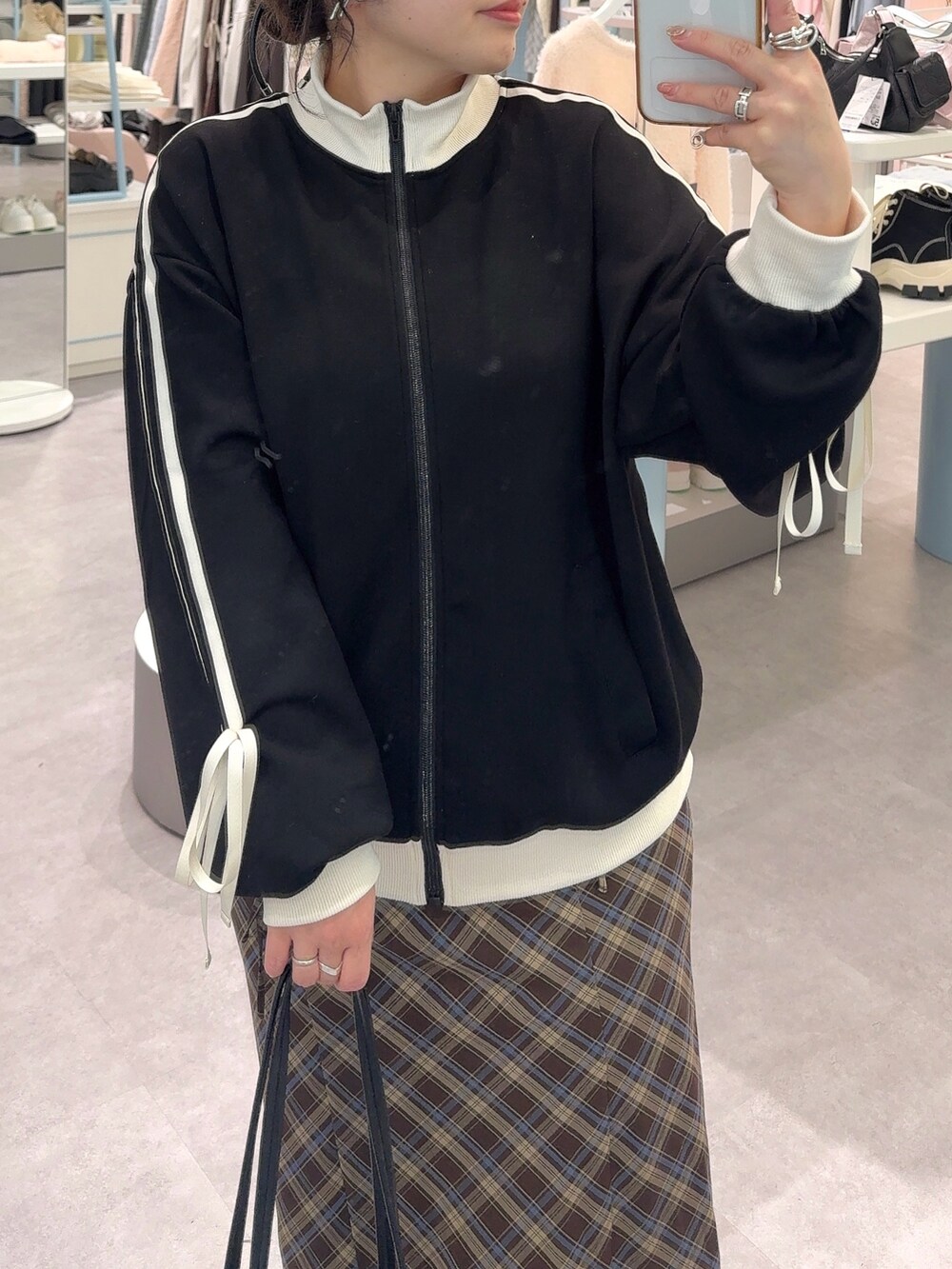 ブラック系のジャージ、ブラウン系のスカート、ブラック系のショルダーバッグを着用したレディースの秋コーディネートの2枚目の写真