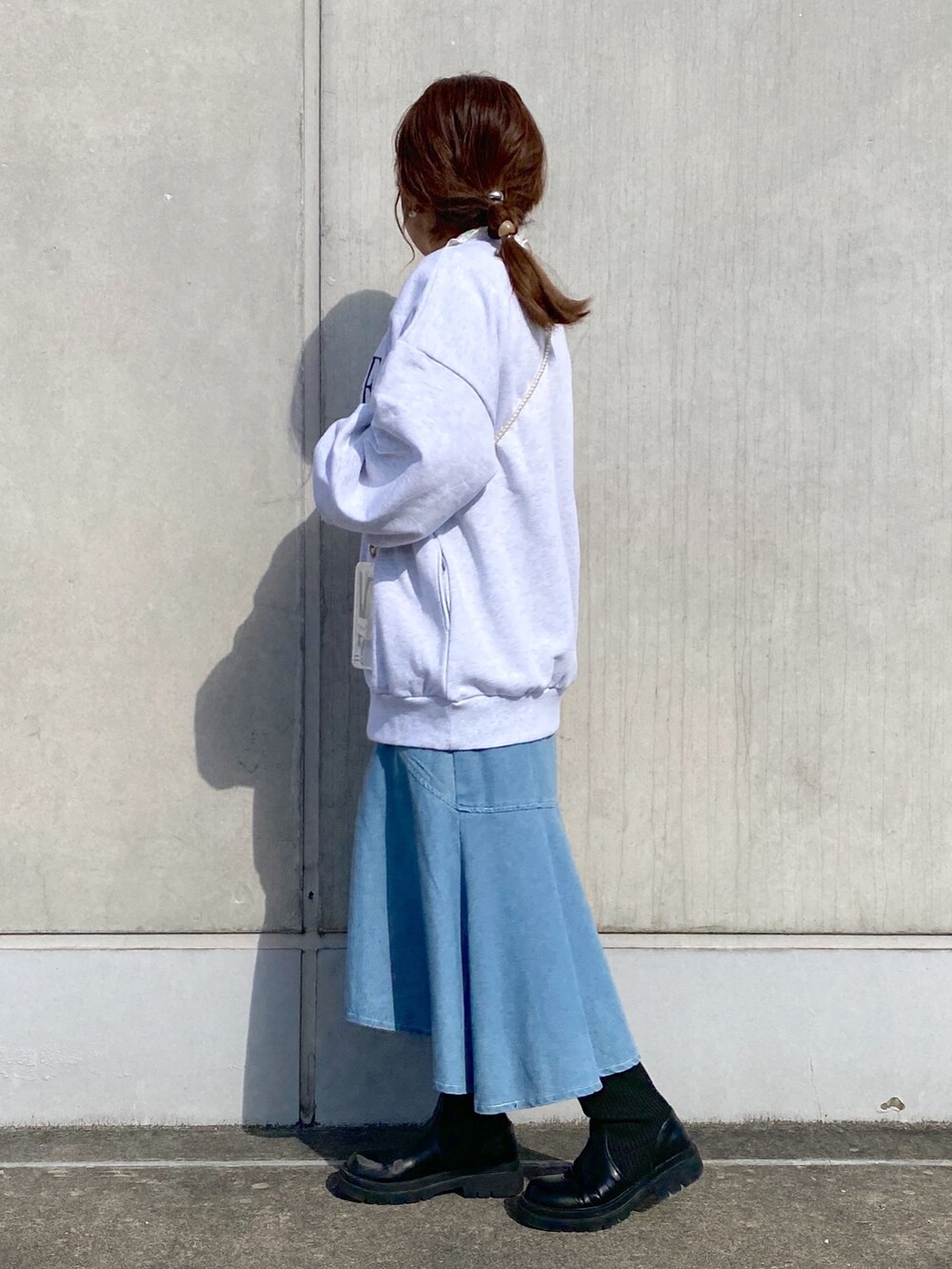 ベージュ系のスウェット、ブルー系のスカート、ブラック系のブーツを着用したレディースの冬コーディネートの2枚目の写真