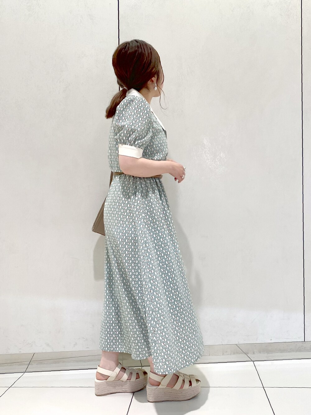 グリーン系のワンピース、ベージュ系のショルダーバッグ、ホワイト系のサンダルを着用したレディースの夏コーディネートの3枚目の写真