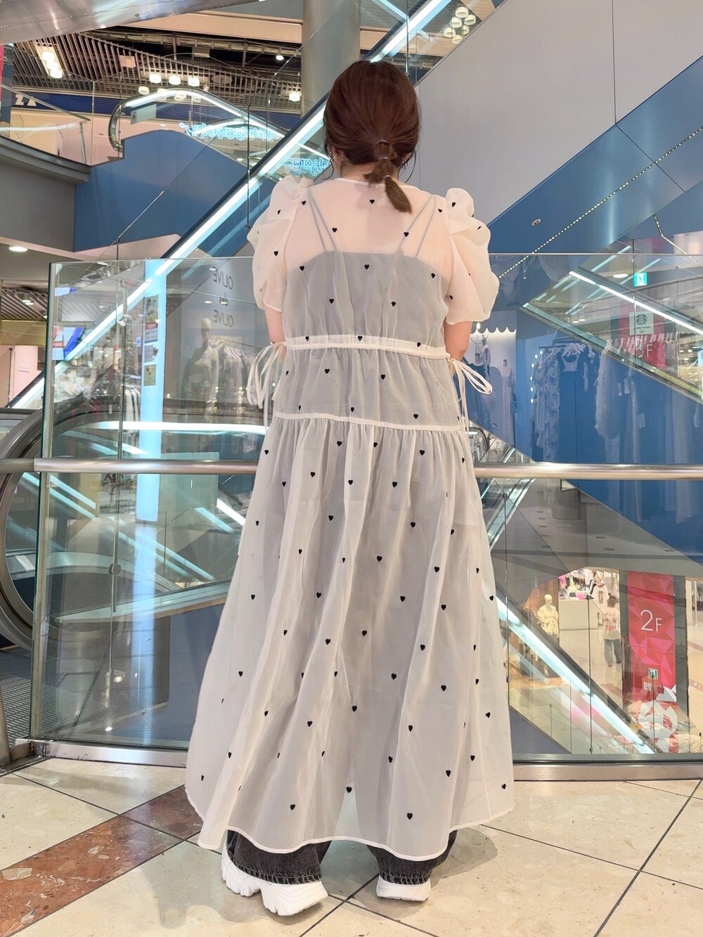 ホワイト系のワンピース、ブラック系のショルダーバッグ、シルバー系のスニーカーを着用したレディースの夏コーディネートの4枚目の写真