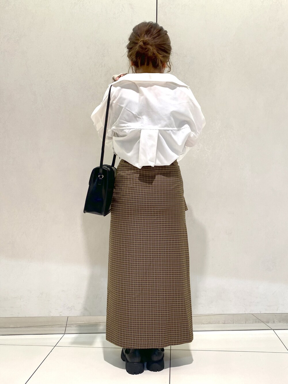 ホワイト系のシャツ/ブラウス、ブラウン系のスカート、ブラック系のブーツを着用したレディースの秋コーディネートの4枚目の写真