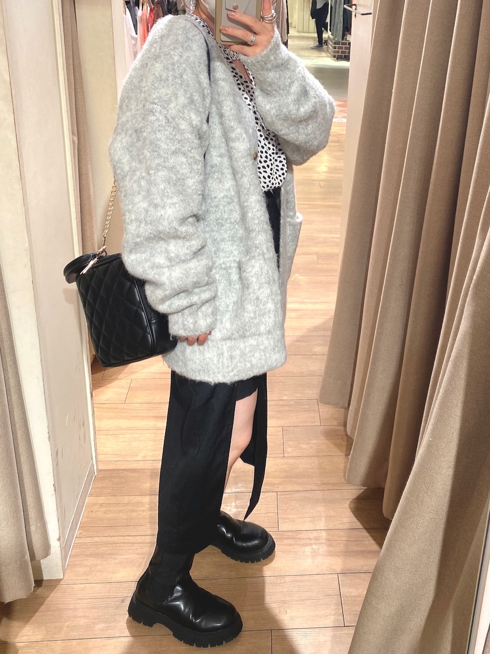 グレー系のカーディガン/ボレロ、ブラック系のスカート、ブラック系のブーツを着用したレディースの秋コーディネートの2枚目の写真