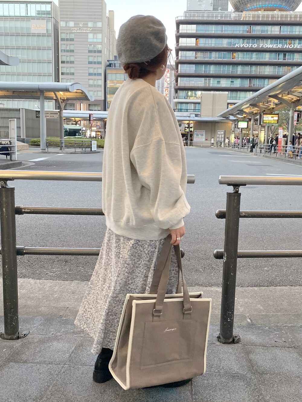 グレー系のスウェット、ブラウン系のトートバッグ、パープル系のワンピースを着用したレディースの秋コーディネートの2枚目の写真