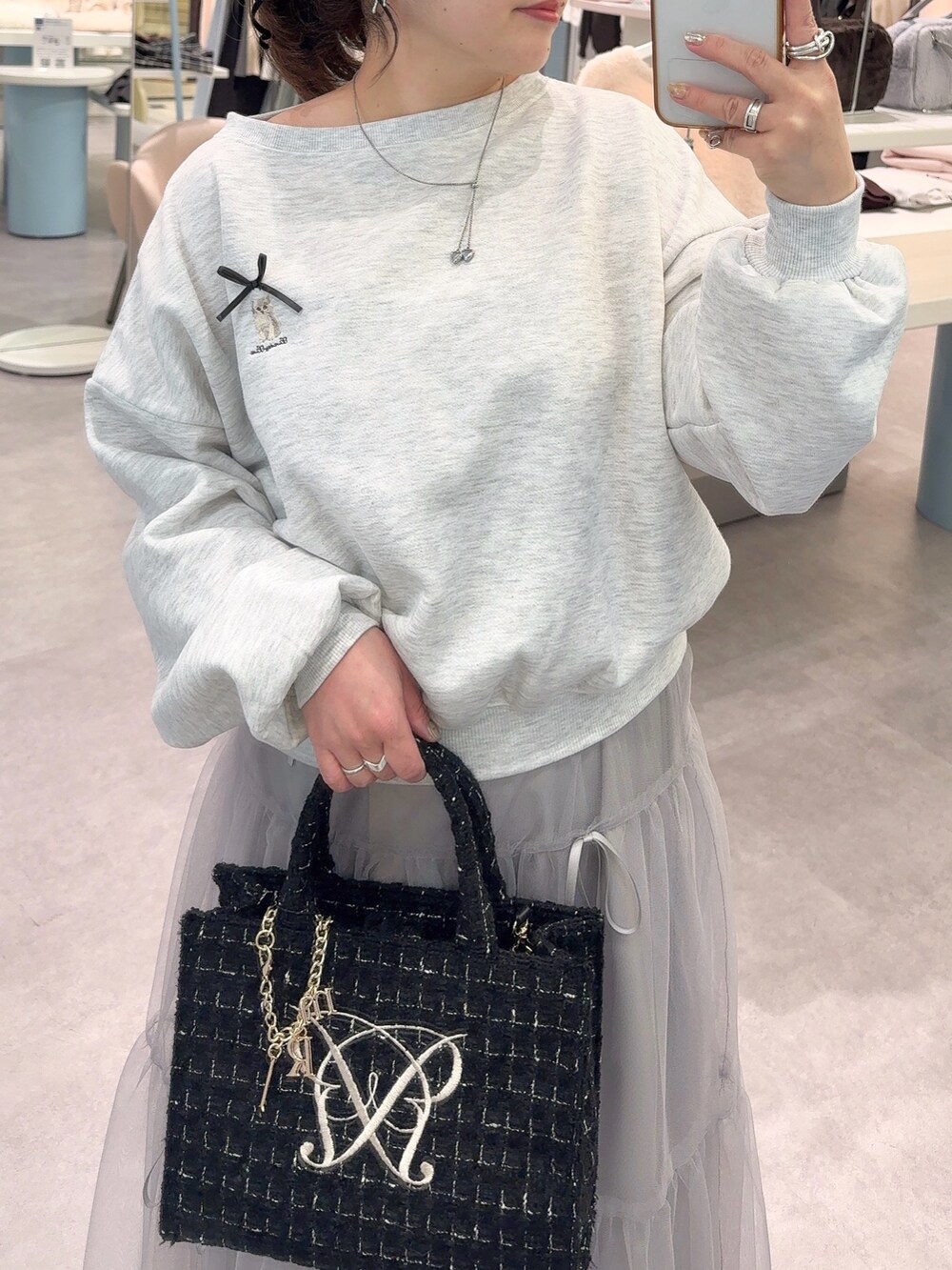 ベージュ系のTシャツ/カットソー、グレー系のスカート、ブラック系のトートバッグを着用したレディースの冬コーディネートの2枚目の写真