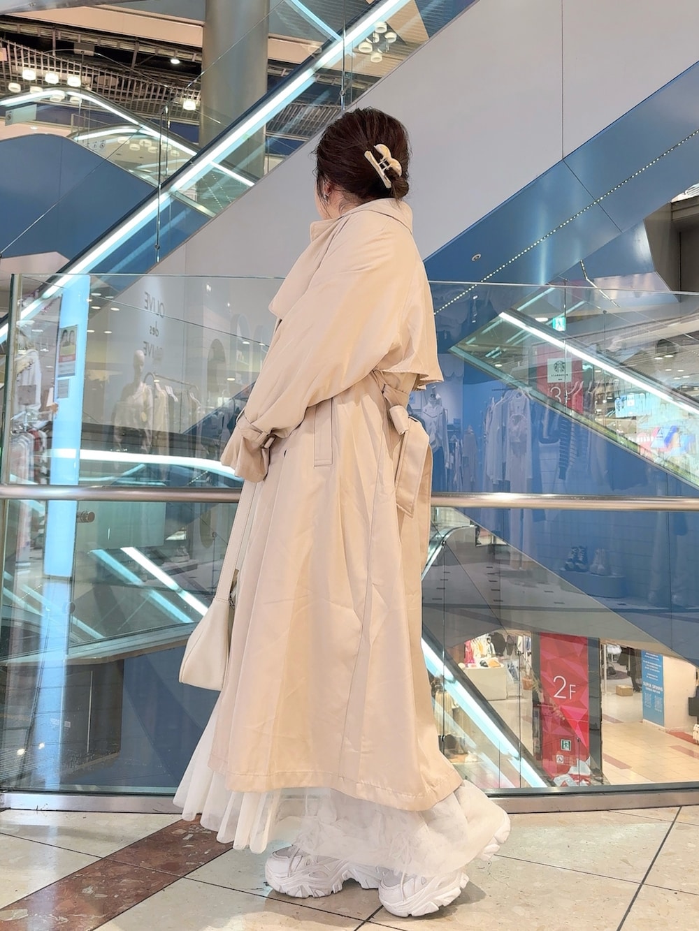 ベージュ系のトレンチコート、ホワイト系のワンピース、ホワイト系のショルダーバッグを着用したレディースの冬コーディネートの2枚目の写真