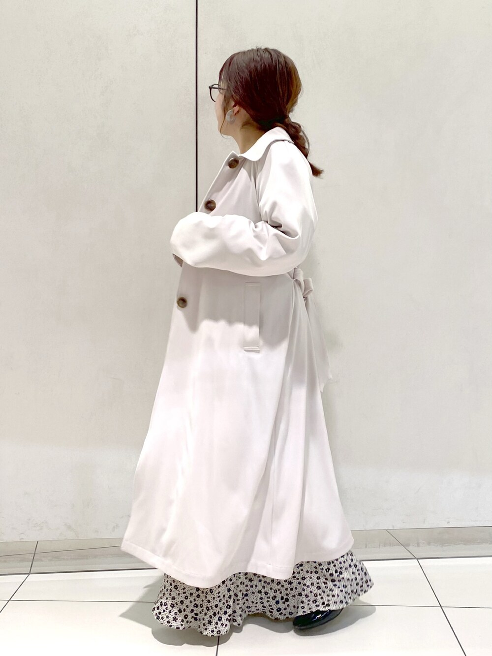 ホワイト系のトレンチコート、ホワイト系のワンピース、ブラック系のバレエシューズを着用したレディースの春コーディネートの2枚目の写真