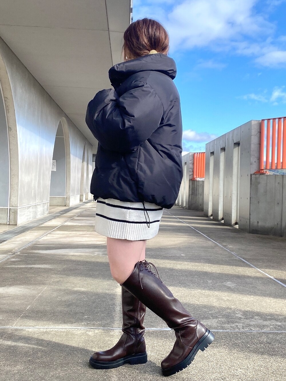 ブラック系のダウンジャケット/コート、ホワイト系のニット/セーター、ブラウン系のブーツを着用したレディースの冬コーディネートの3枚目の写真