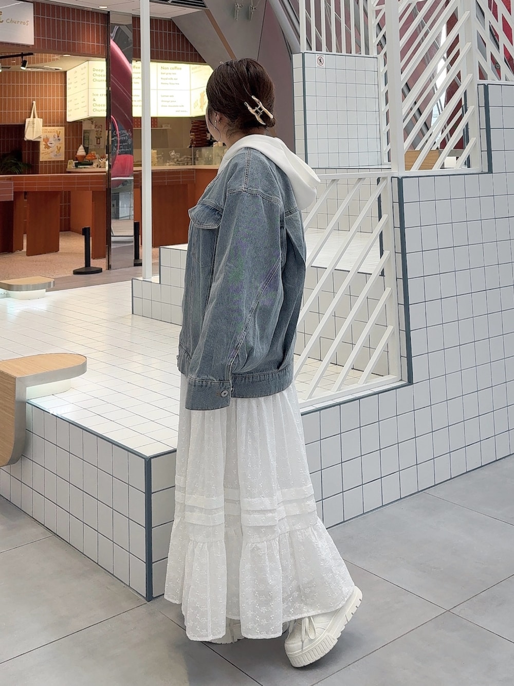 ブルー系のデニムジャケット、ホワイト系のスカート、ホワイト系のスニーカーを着用したレディースの冬コーディネートの2枚目の写真