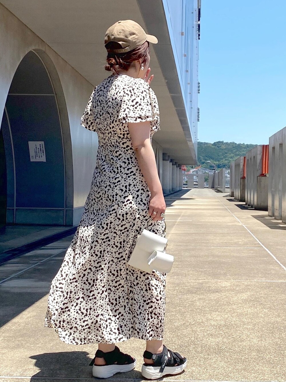 ホワイト系のワンピース、ホワイト系のショルダーバッグ、ブラック系のサンダルを着用したレディースの夏コーディネートの3枚目の写真