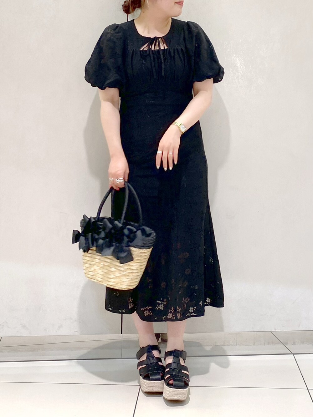ブラック系のワンピース、ブラック系のかごバッグ、ブラック系のサンダルを着用したレディースの春コーディネートの2枚目の写真
