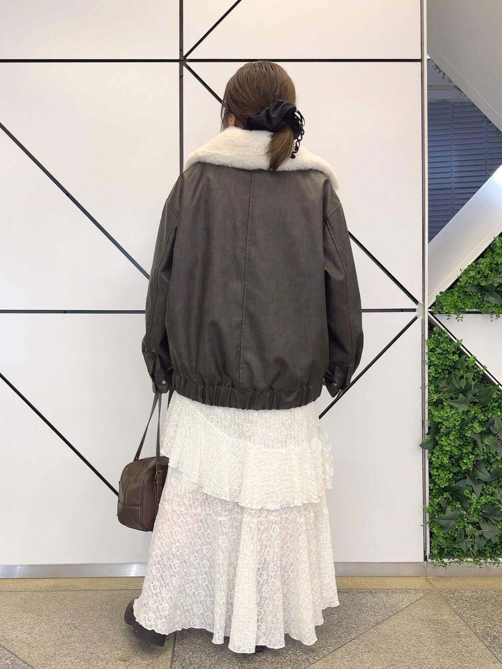 ブラック系のブルゾン、ホワイト系のワンピース、ブラウン系のショルダーバッグを着用したレディースの冬コーディネートの4枚目の写真