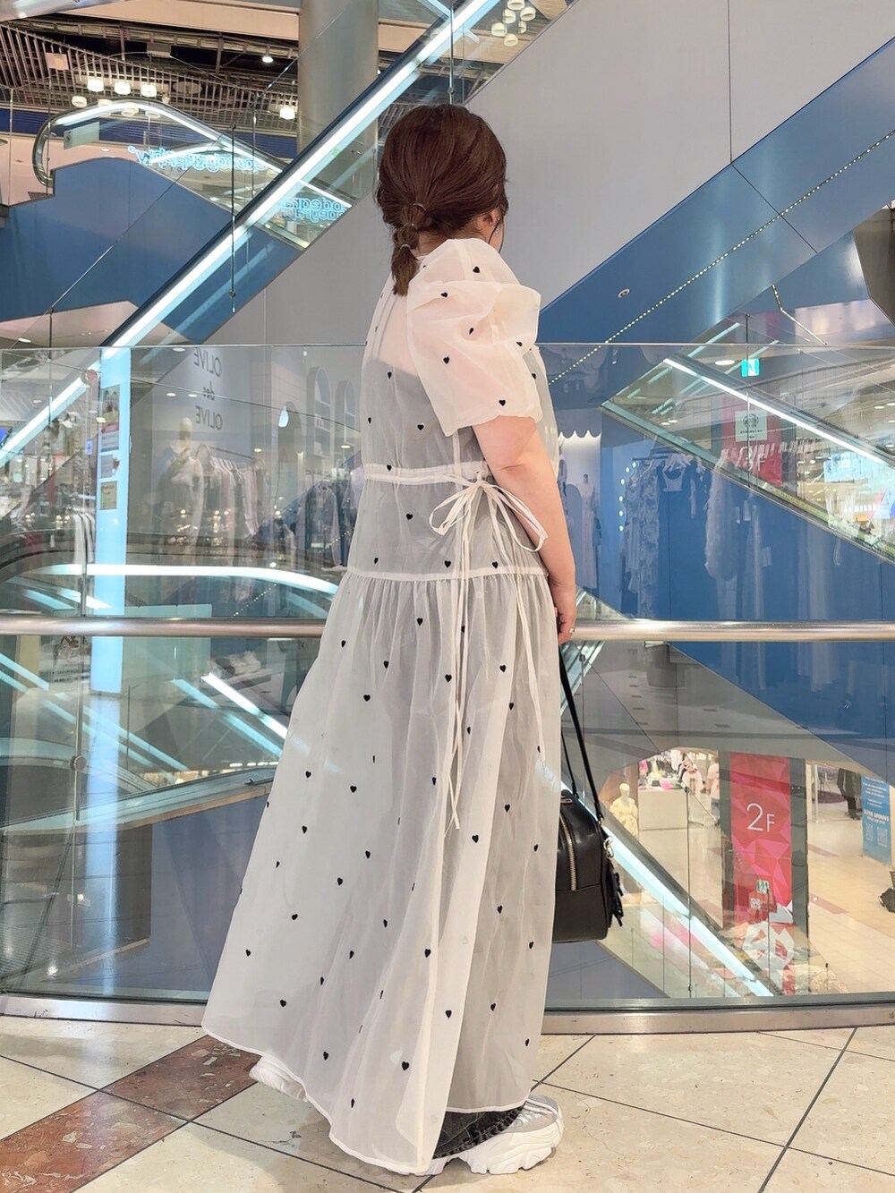 ホワイト系のワンピース、ブラック系のショルダーバッグ、シルバー系のスニーカーを着用したレディースの夏コーディネートの3枚目の写真