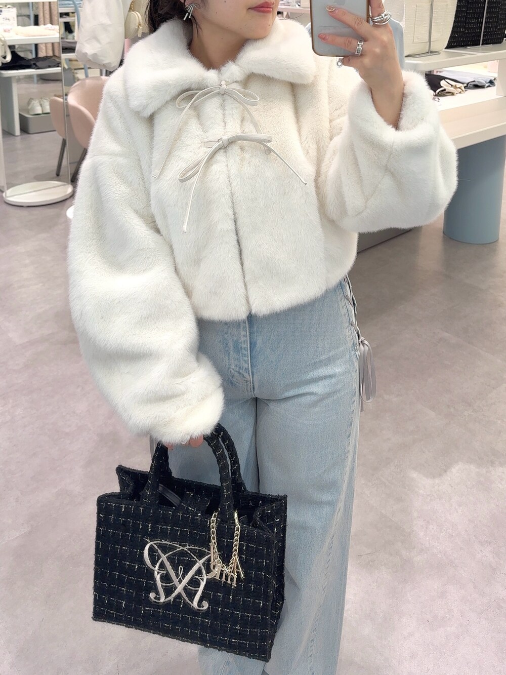 ホワイト系のブルゾン、ブルー系のその他パンツ、ブラック系のトートバッグを着用したレディースの秋コーディネートの2枚目の写真