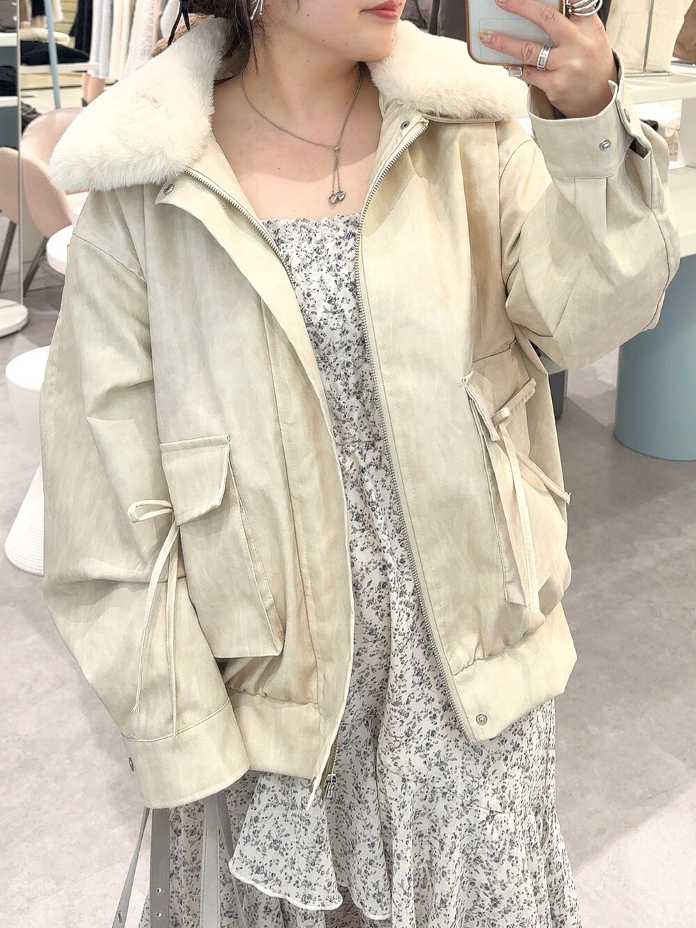 ホワイト系のブルゾン、ホワイト系のワンピース、ブルー系のショルダーバッグを着用したレディースの冬コーディネートの2枚目の写真