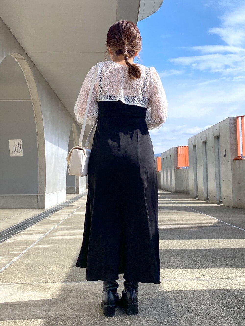 ブラック系のワンピース、ブラック系のブーツ、ホワイト系のショルダーバッグを着用したレディースの冬コーディネートの2枚目の写真