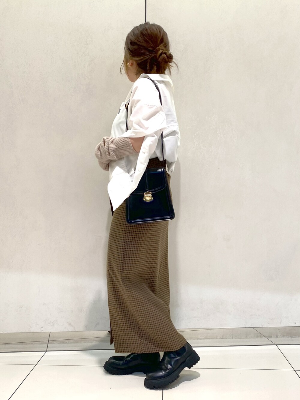 ホワイト系のシャツ/ブラウス、ブラウン系のスカート、ブラック系のブーツを着用したレディースの秋コーディネートの3枚目の写真