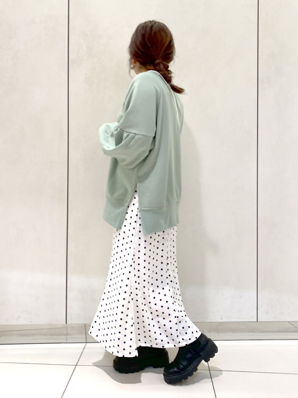グリーン系のカーディガン/ボレロ、ホワイト系のスカート、ブラック系のブーツを着用したレディースの春コーディネートの2枚目の写真