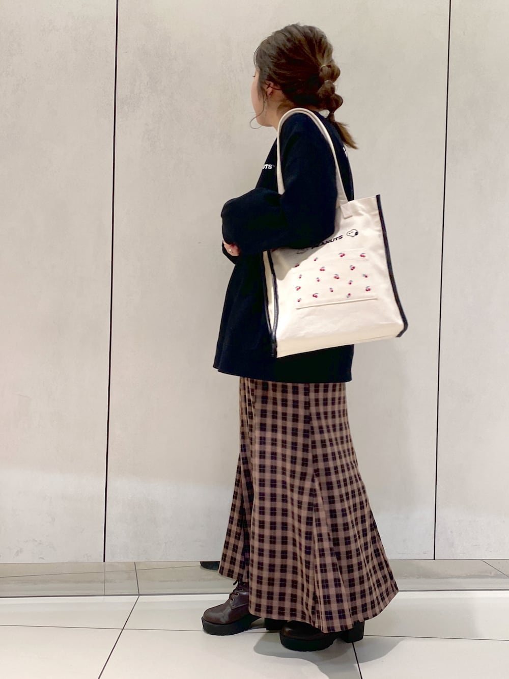 ホワイト系のトートバッグ、ブラック系のスウェット、ブラウン系のスカートを着用したレディースの秋コーディネートの3枚目の写真