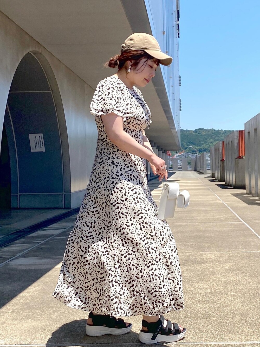 ホワイト系のワンピース、ホワイト系のショルダーバッグ、ブラック系のサンダルを着用したレディースの夏コーディネートの2枚目の写真