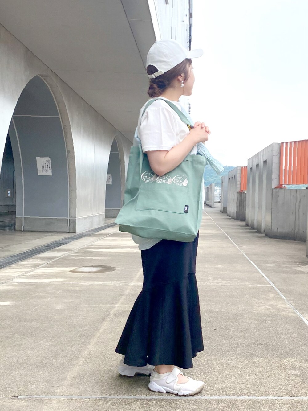 イエロー系のTシャツ/カットソー、ブラック系のスカート、ベージュ系のスニーカーを着用したレディースの夏コーディネートの3枚目の写真