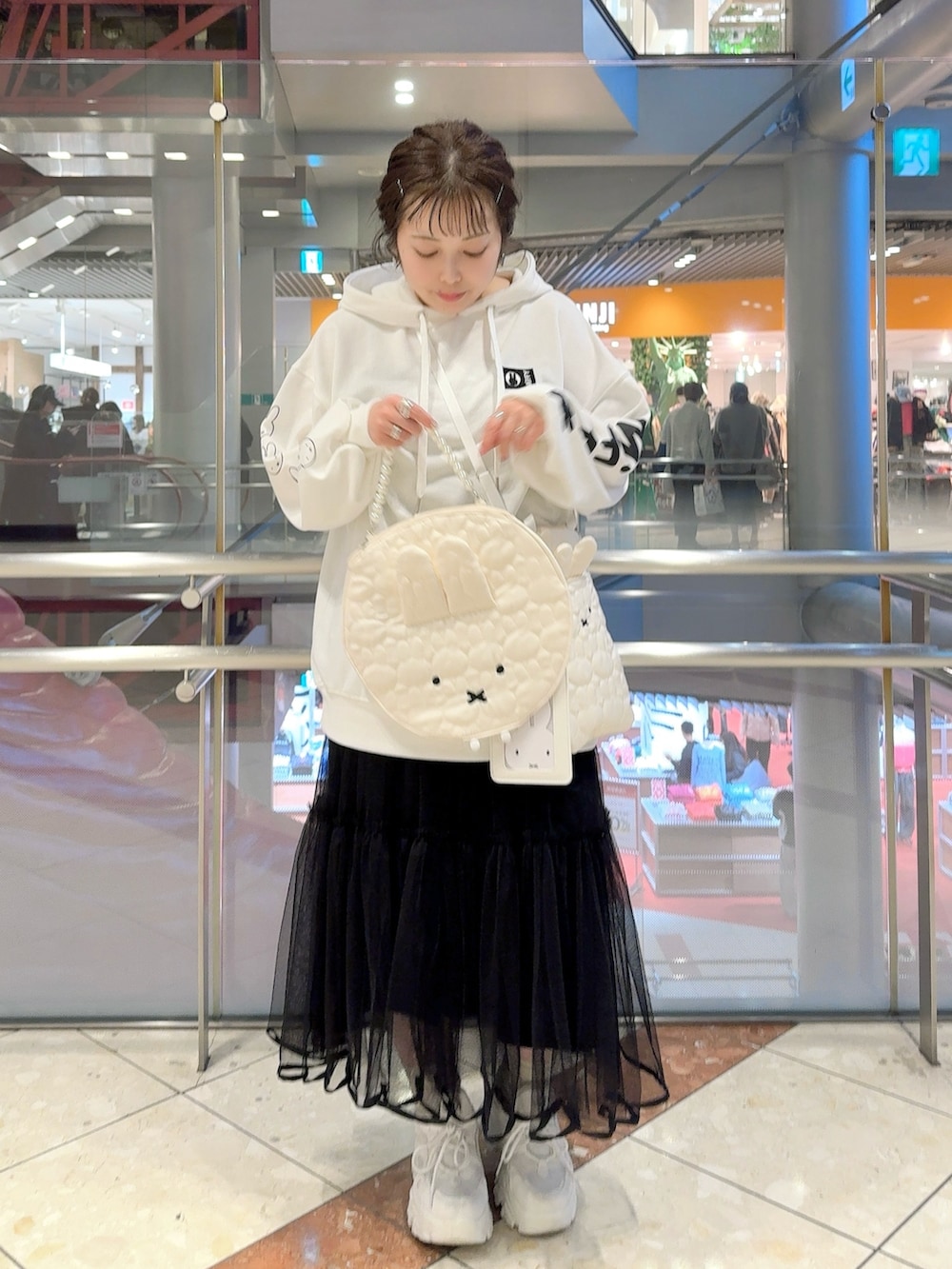 ホワイト系のパーカー、ホワイト系のショルダーバッグ、ホワイト系のハンドバッグを着用したレディースの冬コーディネートの2枚目の写真