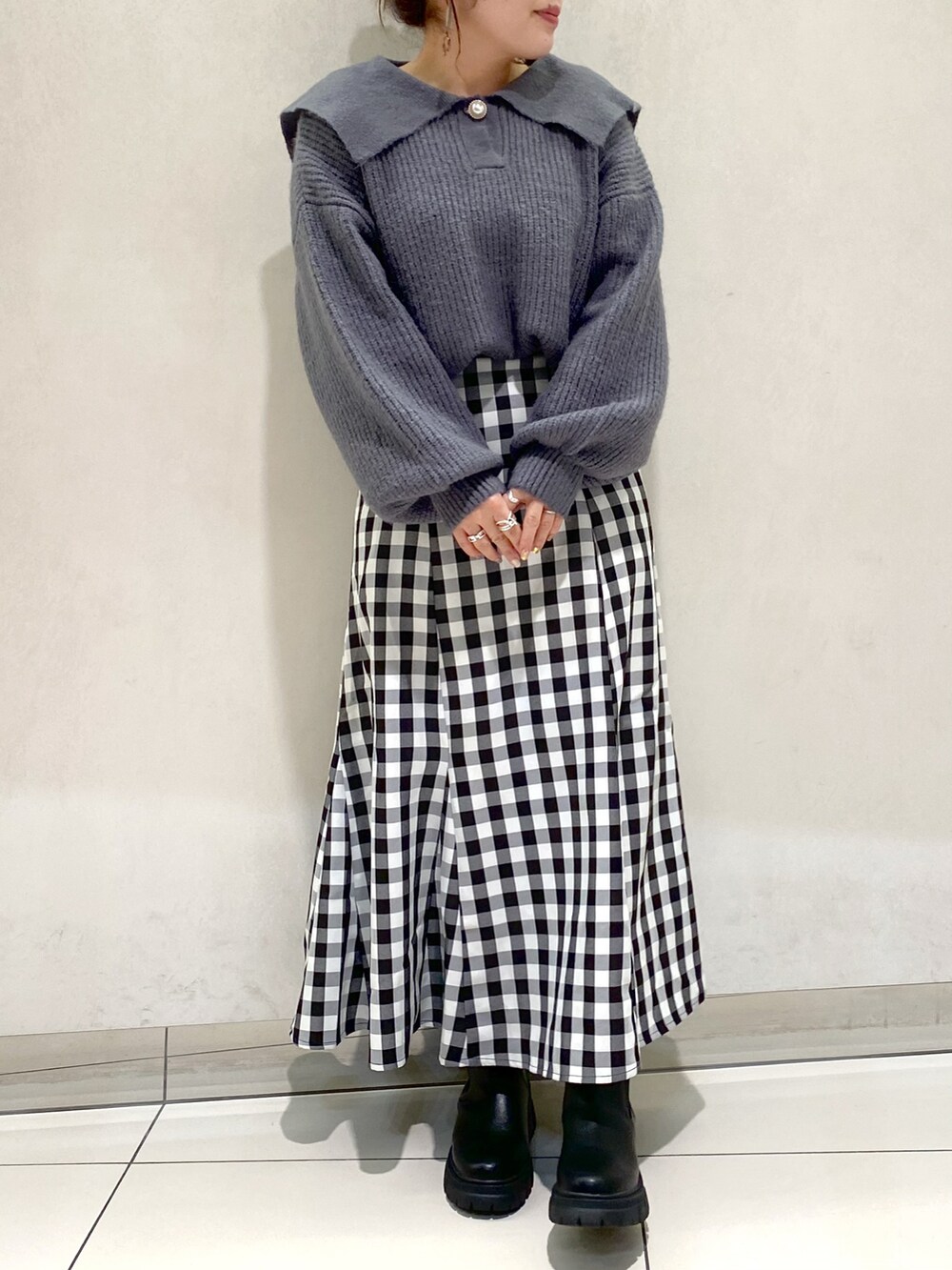 グレー系のステンカラーコート、ホワイト系のニット/セーター、ブラック系のブーツを着用したレディースの冬コーディネートの3枚目の写真