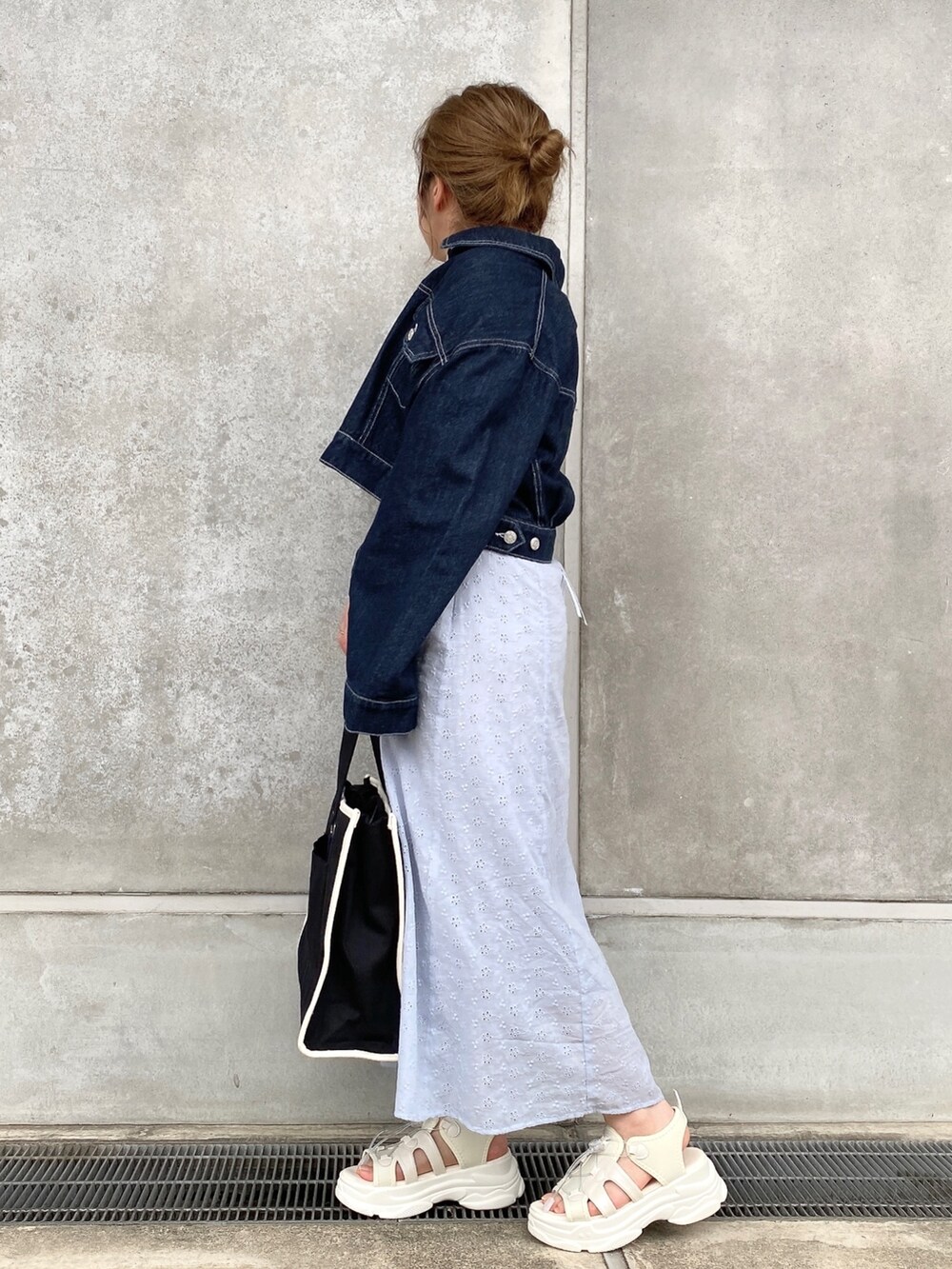 ブルー系のデニムジャケット、ブルー系のワンピース、ブラック系のトートバッグを着用したレディースの春コーディネートの2枚目の写真