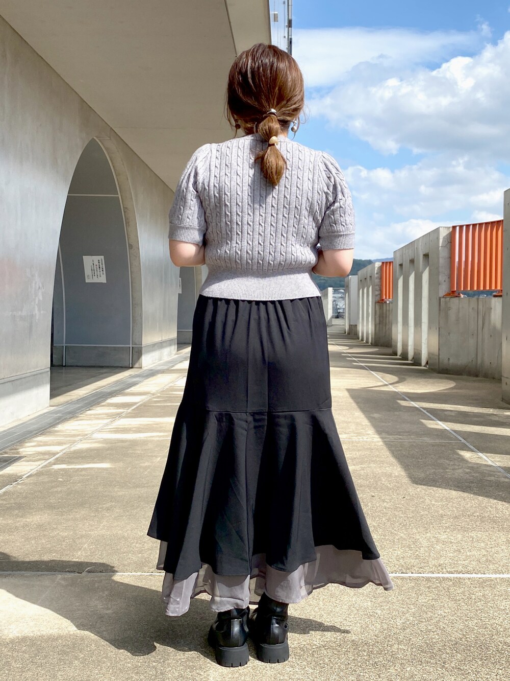 グレー系のニット/セーター、ベージュ系のショルダーバッグ、ブラック系のスカートを着用したレディースの秋コーディネートの3枚目の写真