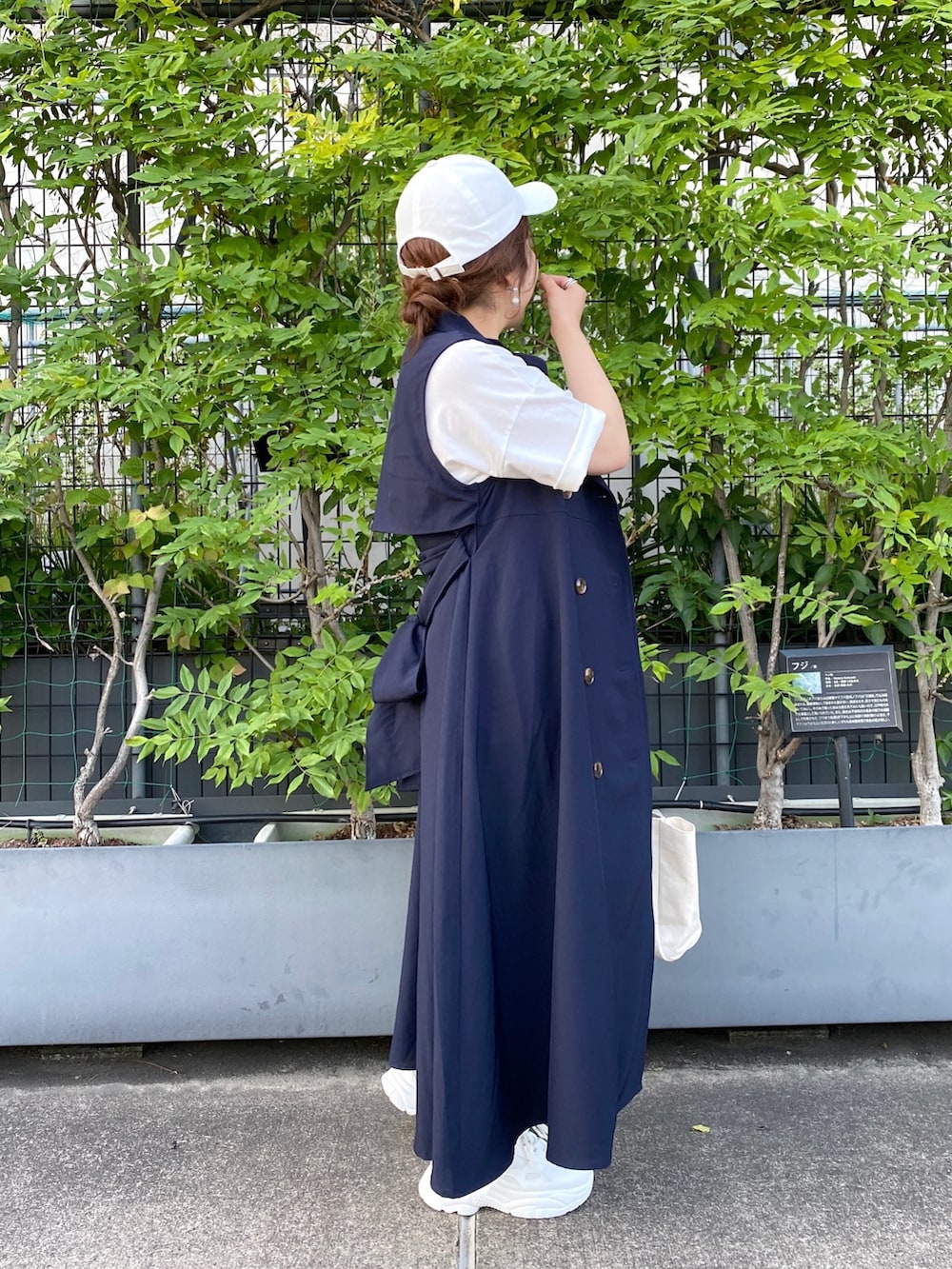 ブルー系のワンピース、ホワイト系のトートバッグ、ホワイト系のスニーカーを着用したレディースの春コーディネートの2枚目の写真