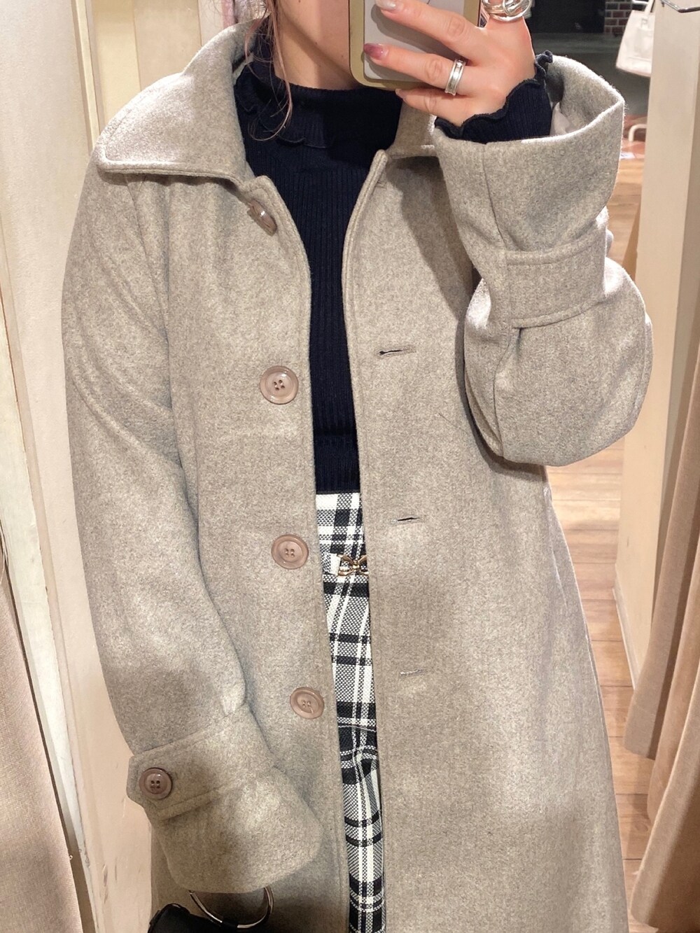 ブラウン系のステンカラーコート、ブラック系のニット/セーター、その他のスカートを着用したレディースの冬コーディネートの2枚目の写真