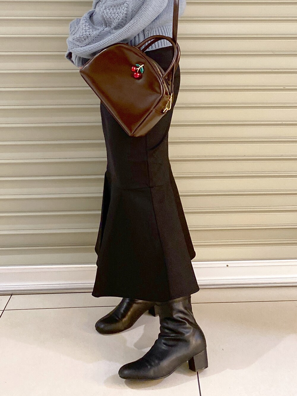 ブルー系のニット/セーター、ブラウン系のショルダーバッグ、ブラック系のスカートを着用したレディースの秋コーディネートの3枚目の写真