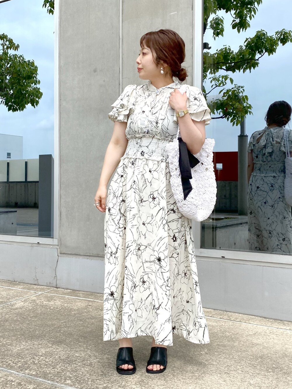 ホワイト系のワンピース、ホワイト系のかごバッグ、ブラック系のサンダルを着用したレディースの夏コーディネートの2枚目の写真