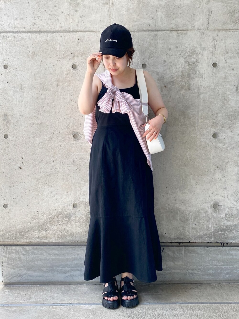 ブラック系のワンピース、ブラック系のサンダル、ホワイト系のショルダーバッグを着用したレディースの夏コーディネートの2枚目の写真