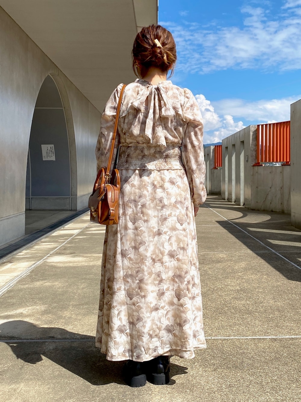 ブラウン系のワンピース、ブラック系のブーツ、イエロー系のショルダーバッグを着用したレディースの秋コーディネートの3枚目の写真