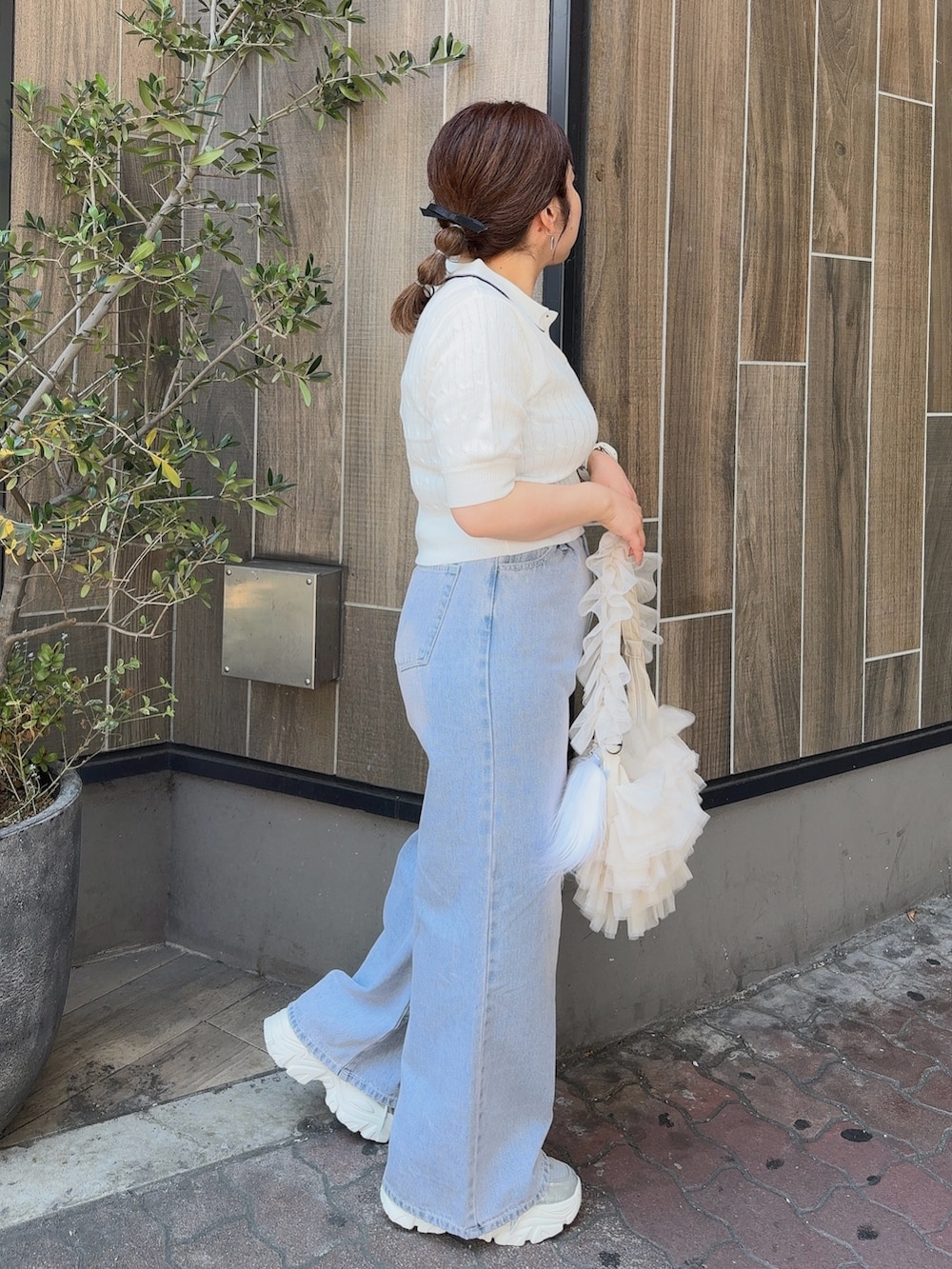 ホワイト系のニット/セーター、ブルー系のデニムパンツ、ホワイト系のショルダーバッグを着用したレディースの夏コーディネートの2枚目の写真