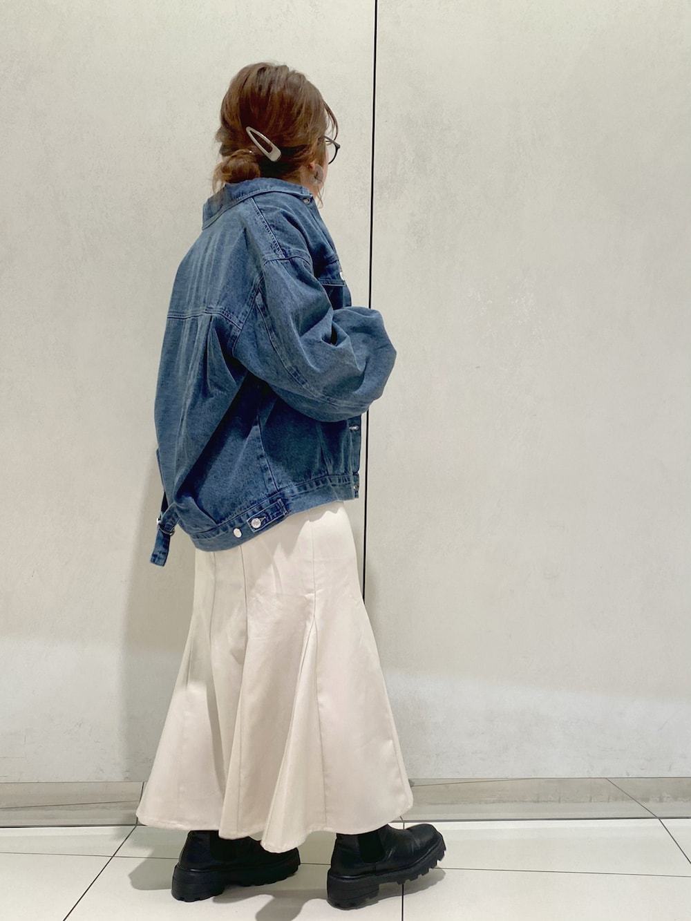 ブルー系のデニムジャケット、グレー系のカーディガン/ボレロ、ホワイト系のスカートを着用したレディースの春コーディネートの2枚目の写真