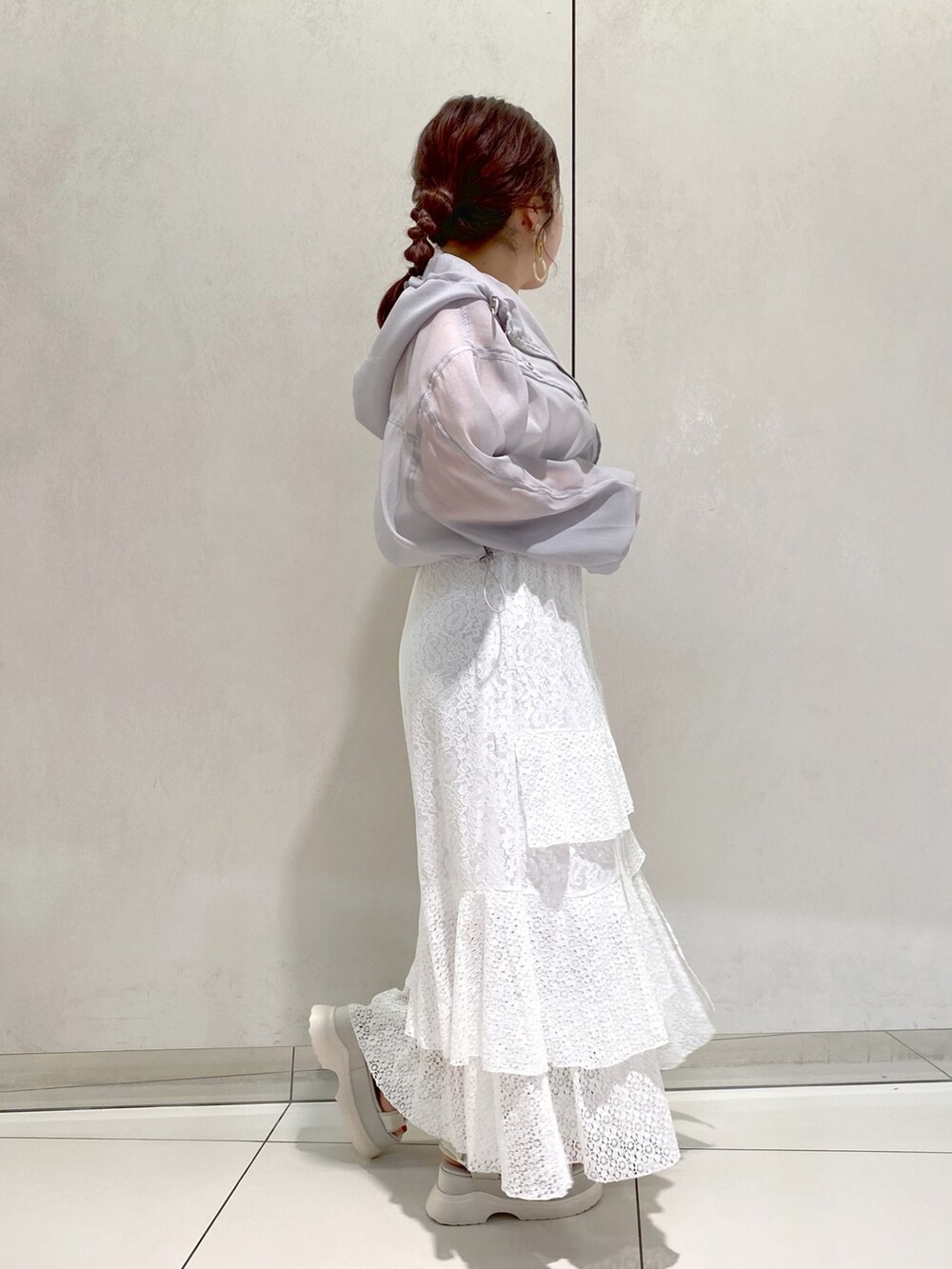 ホワイト系のスカート、ホワイト系のサンダル、グレー系のマウンテンパーカーを着用したレディースの春コーディネートの2枚目の写真