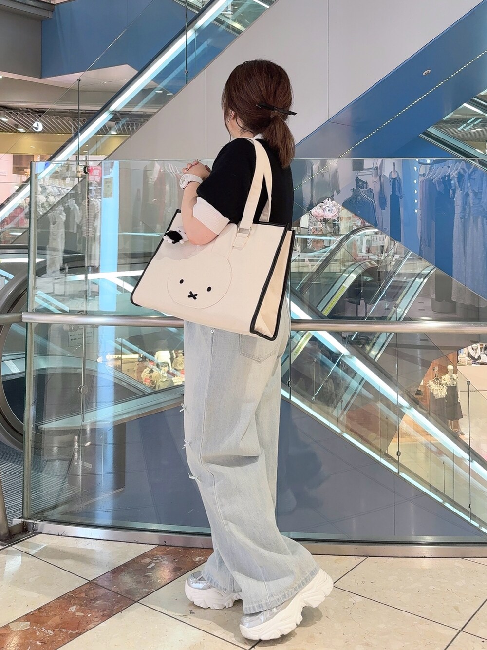 ベージュ系のトートバッグ、ブラック系のニット/セーター、ブルー系のその他パンツを着用したレディースの夏コーディネートの3枚目の写真