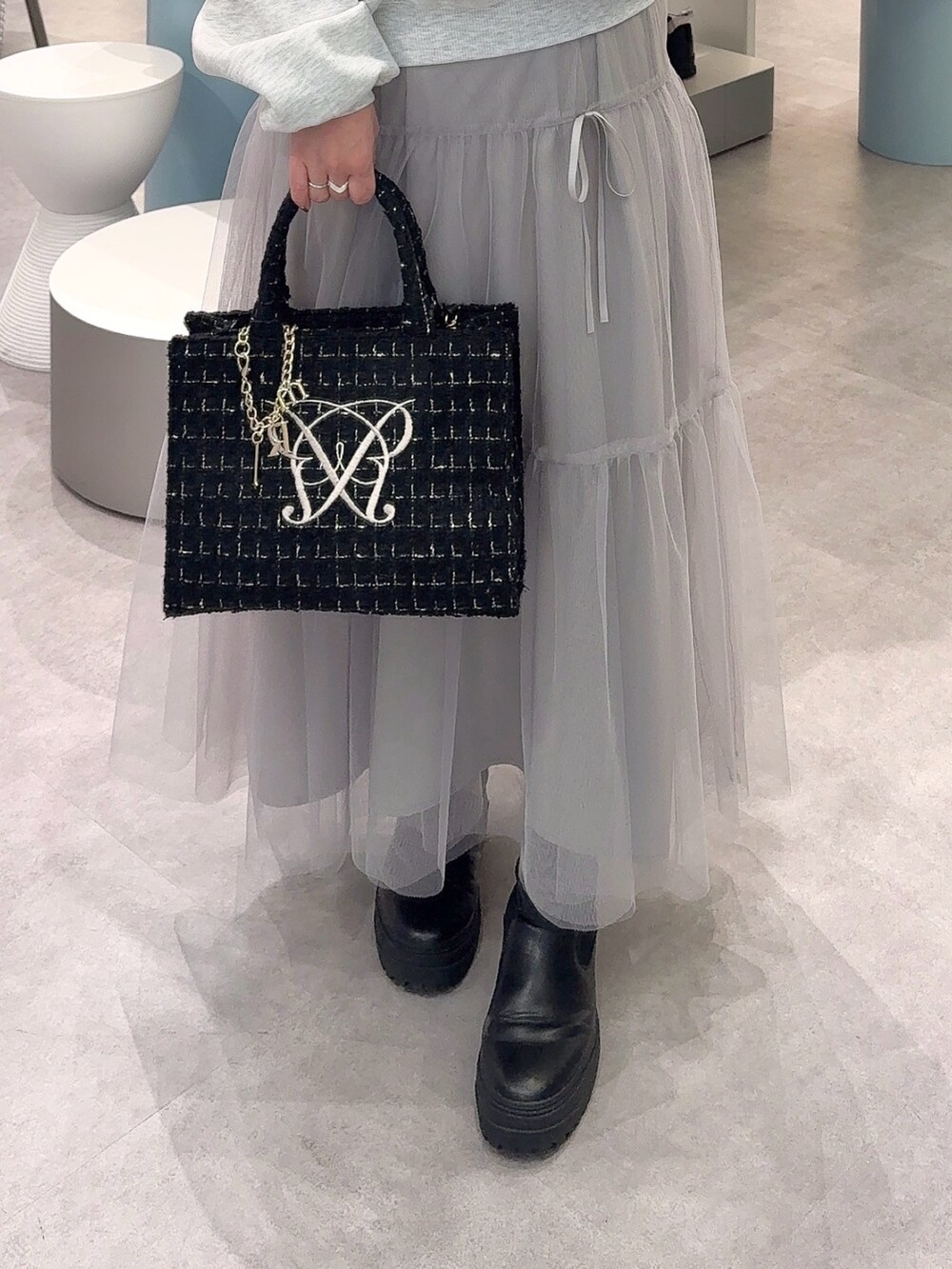 ベージュ系のTシャツ/カットソー、グレー系のスカート、ブラック系のトートバッグを着用したレディースの冬コーディネートの3枚目の写真