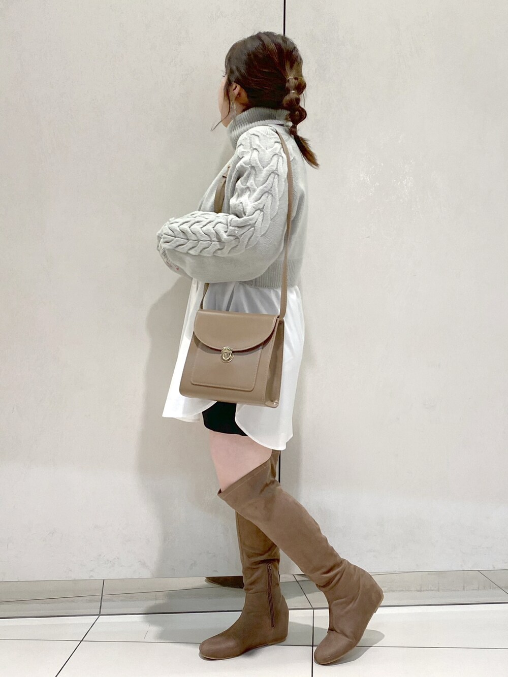 グリーン系のTシャツ/カットソー、ベージュ系のショルダーバッグ、ベージュ系のブーツを着用したレディースの冬コーディネートの2枚目の写真