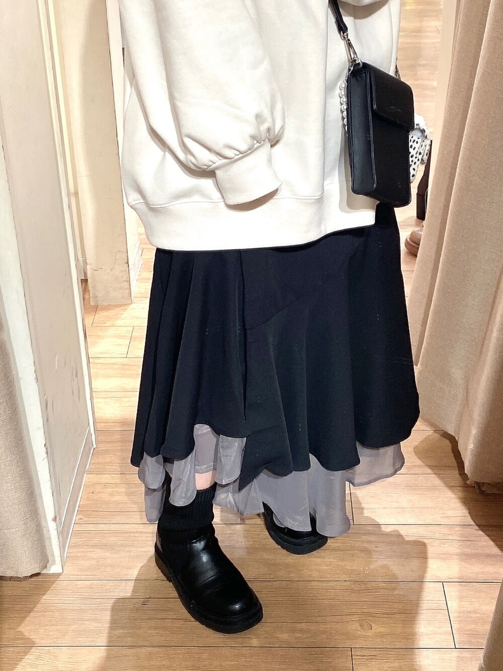 ホワイト系のスウェット、ブラック系のスカート、ブラック系のブーツを着用したレディースの冬コーディネートの3枚目の写真