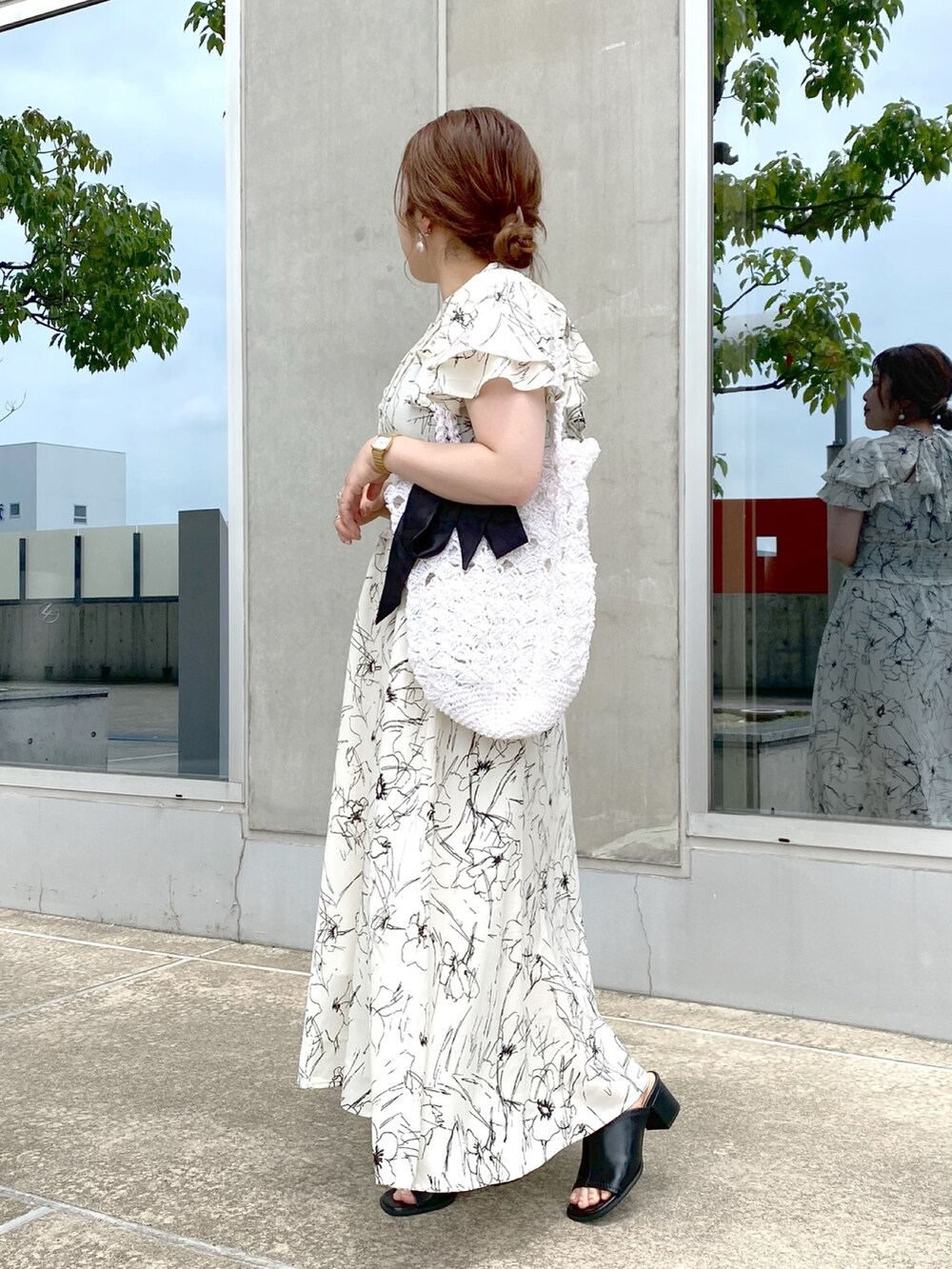 ホワイト系のワンピース、ホワイト系のかごバッグ、ブラック系のサンダルを着用したレディースの夏コーディネートの3枚目の写真