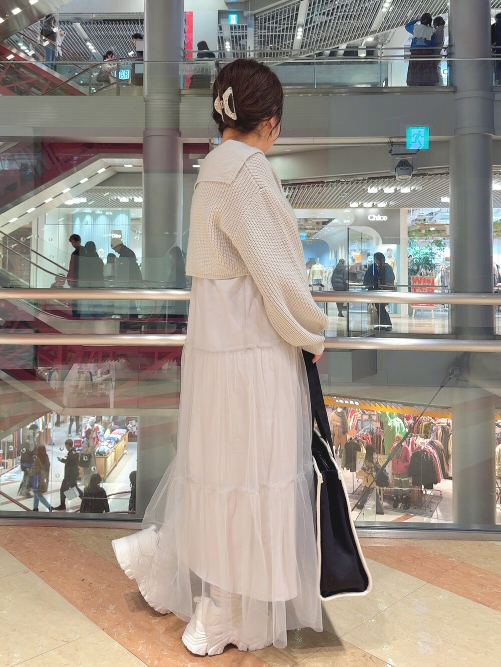 グリーン系のワンピース、ブラック系のトートバッグ、ホワイト系のスニーカーを着用したレディースの冬コーディネートの2枚目の写真