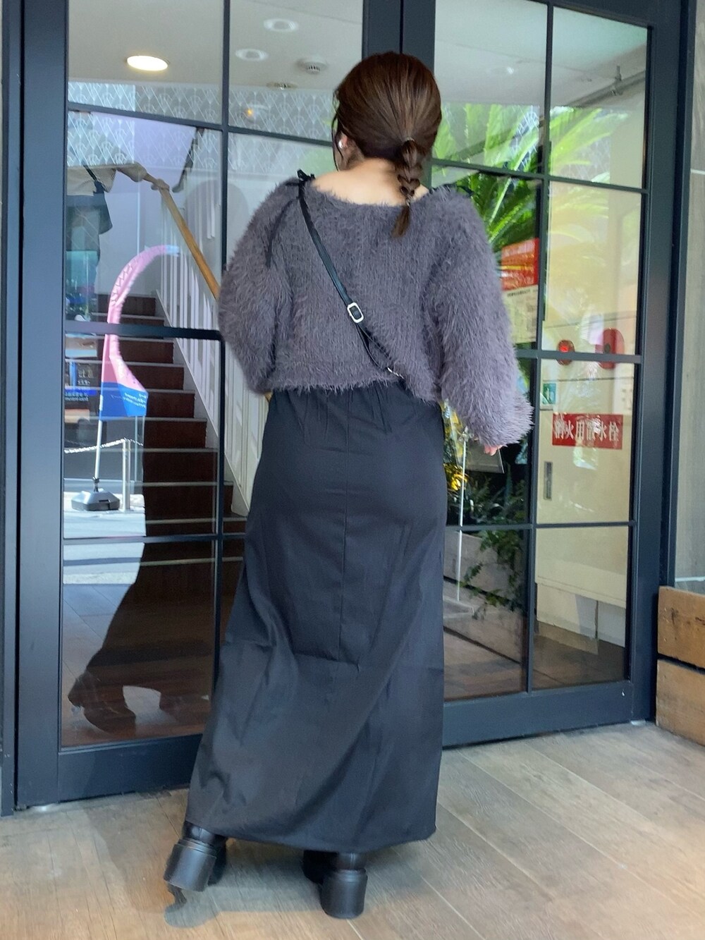 グレー系のワンピース、ブラック系のショルダーバッグ、ブラック系のブーツを着用したレディースの秋コーディネートの4枚目の写真