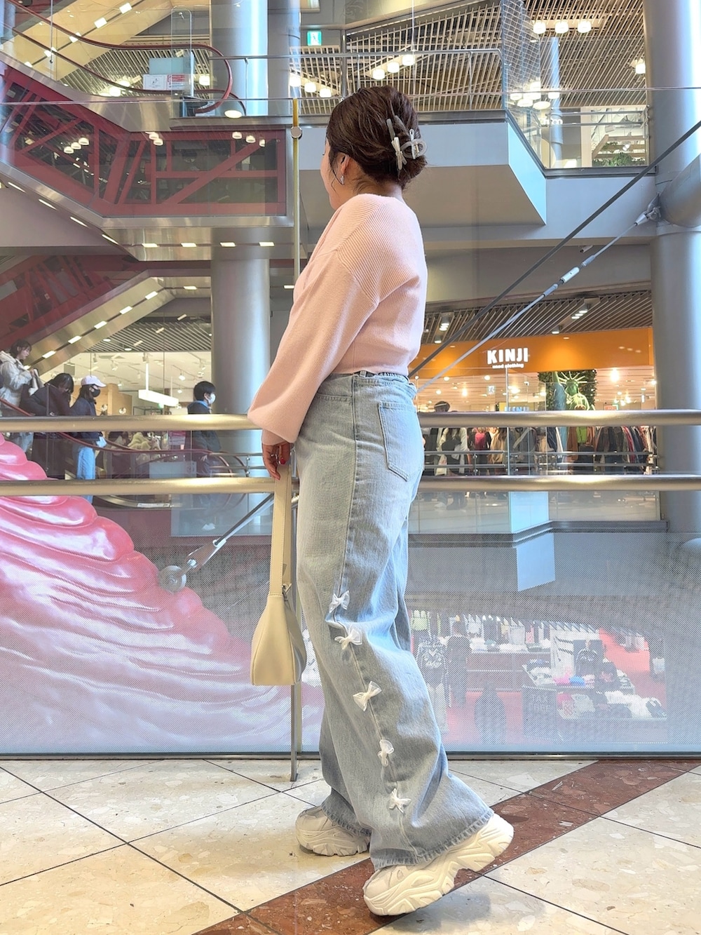 ピンク系のカーディガン/ボレロ、ブルー系のデニムパンツ、ホワイト系のショルダーバッグを着用したレディースの冬コーディネートの3枚目の写真